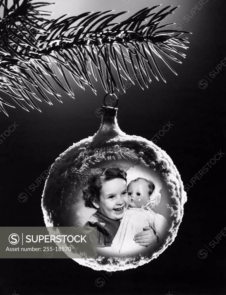Close-up of an image of a girl hugging a doll superimposed on a Christmas ornament