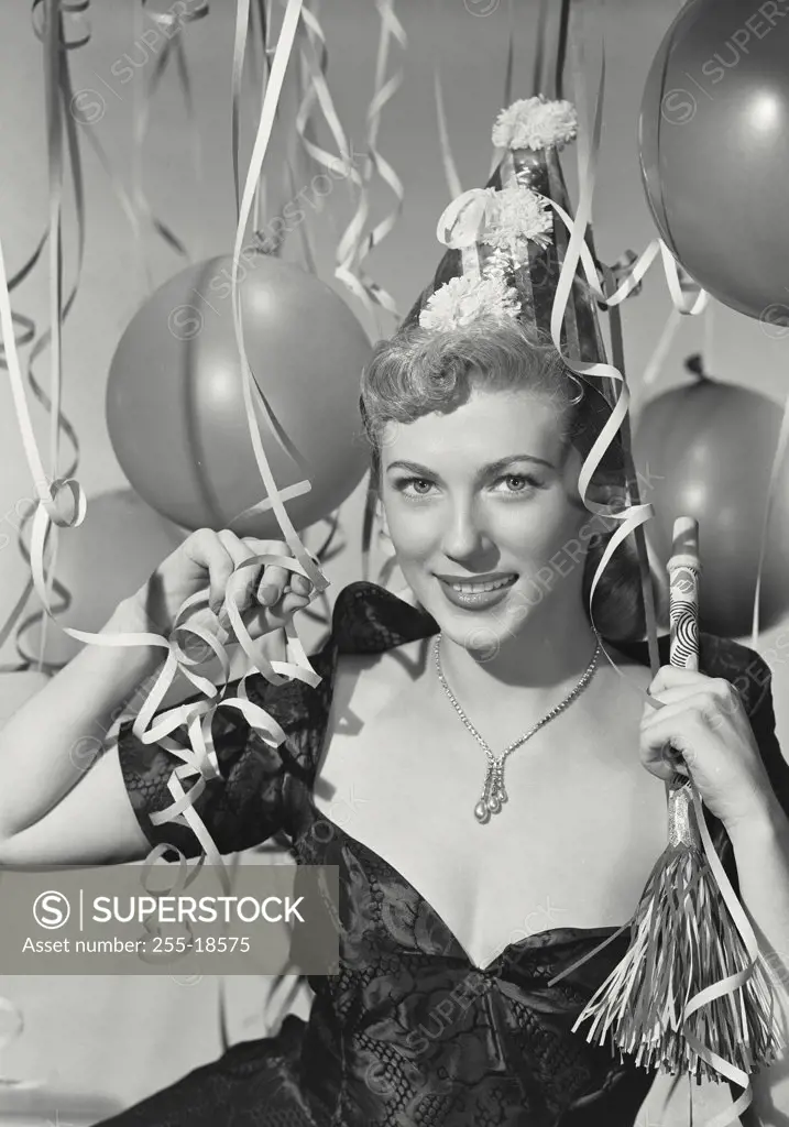 Vintage photograph. Woman in party hat holding party blower in party scene