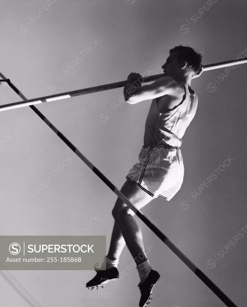 Low angle view of a young man pole vaulting