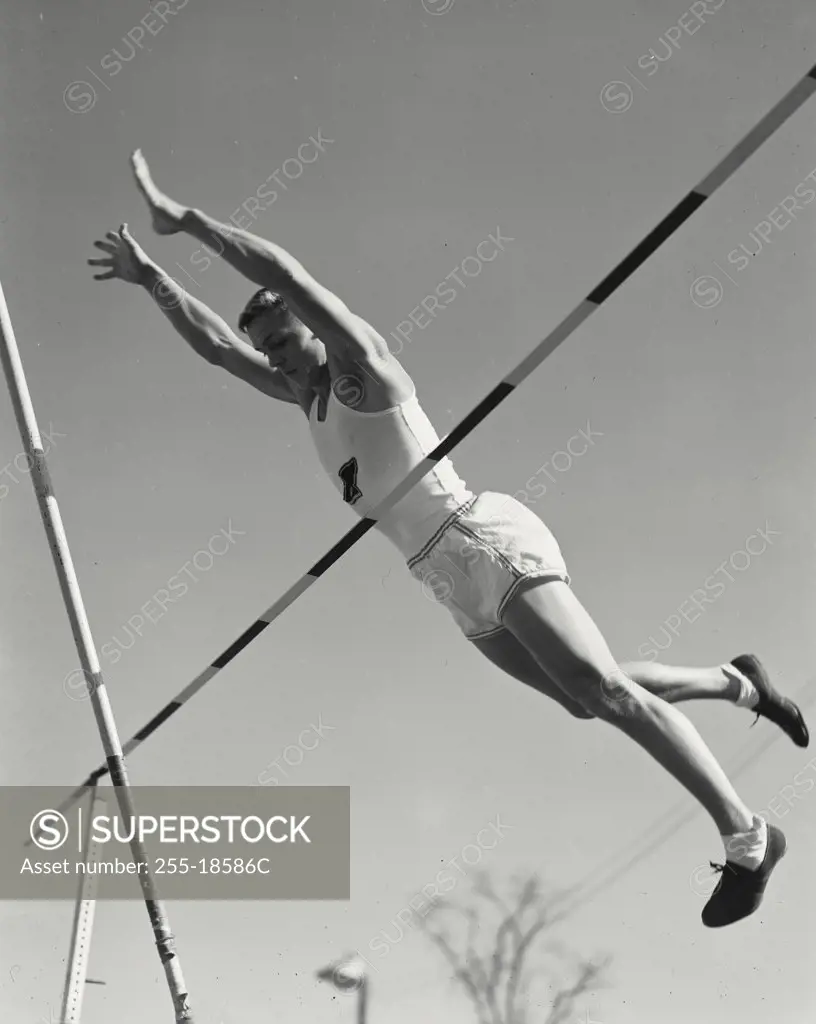 Vintage photograph. Pole vaulter clearing crossbar.