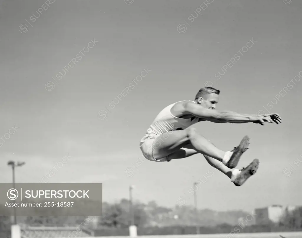 Vintage photograph. Runner in mid air for long jump.