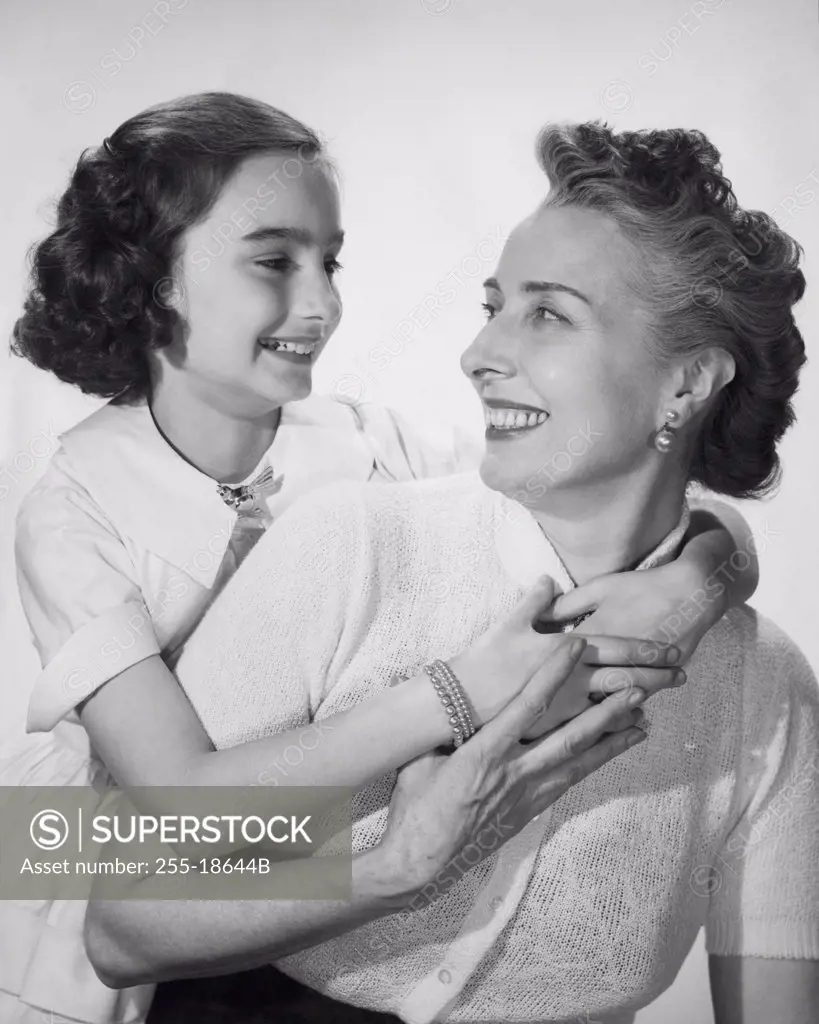 Studio shot of girl hugging her grandmother and smiling