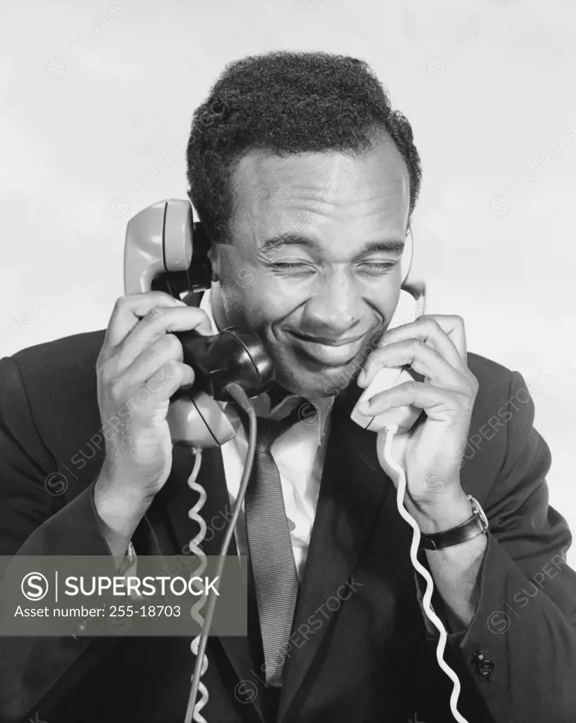 Close-up of a businessman using three telephones at a time