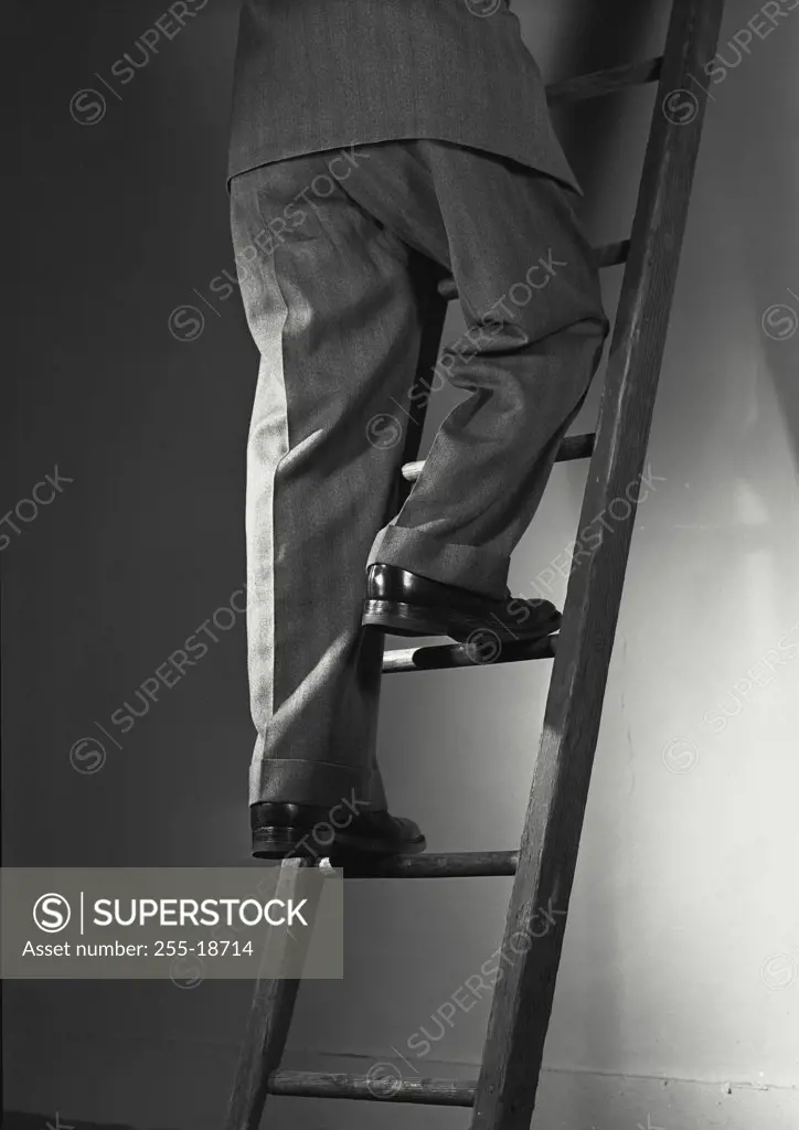 Vintage photograph. Low section view of a businessman climbing up a ladder