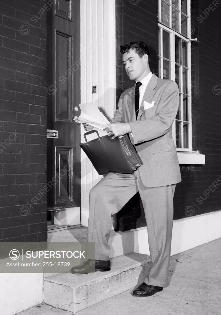 Insurance agent at front door, holding documents