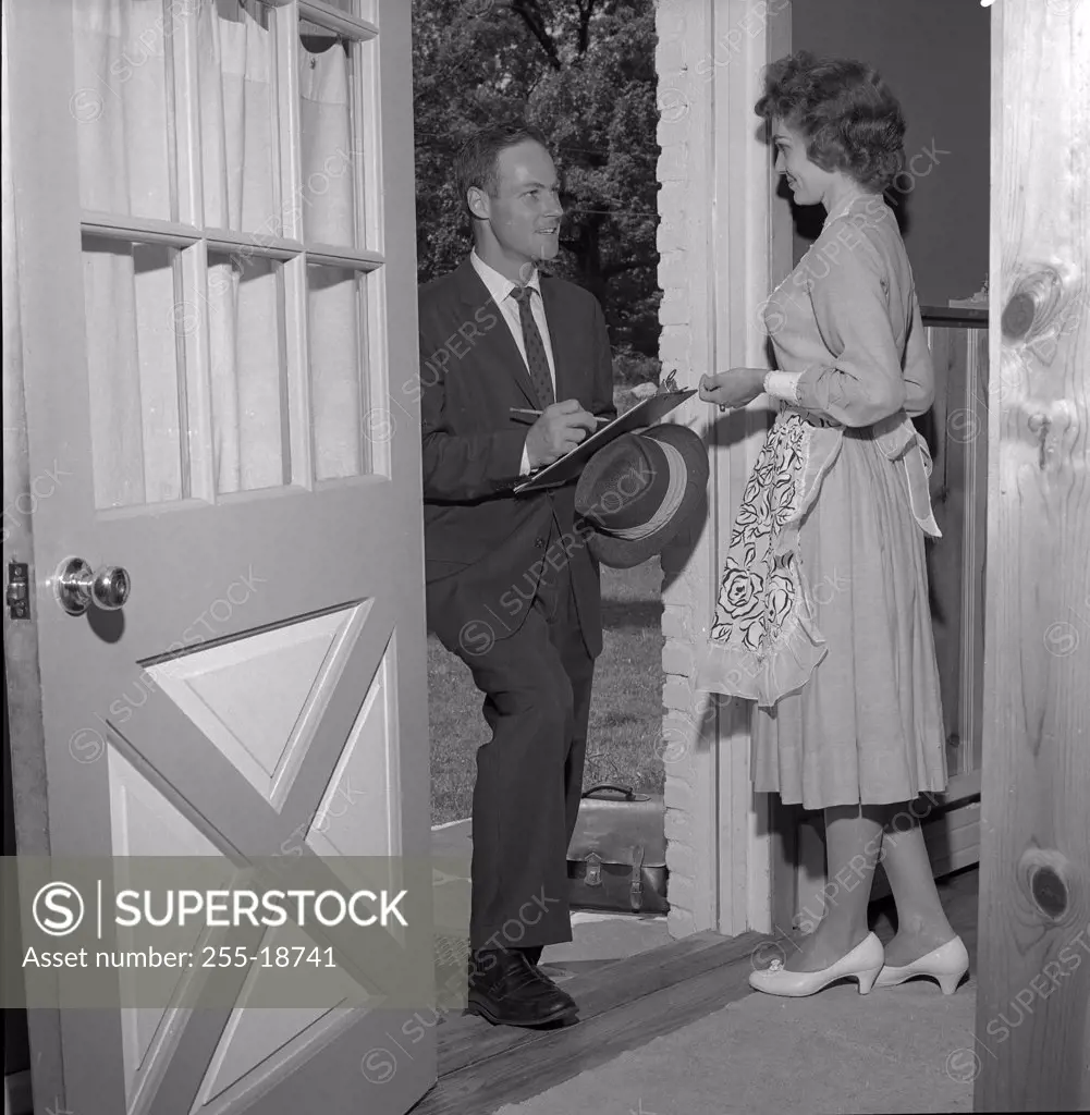 Insurance agent talking to young housewife at front door