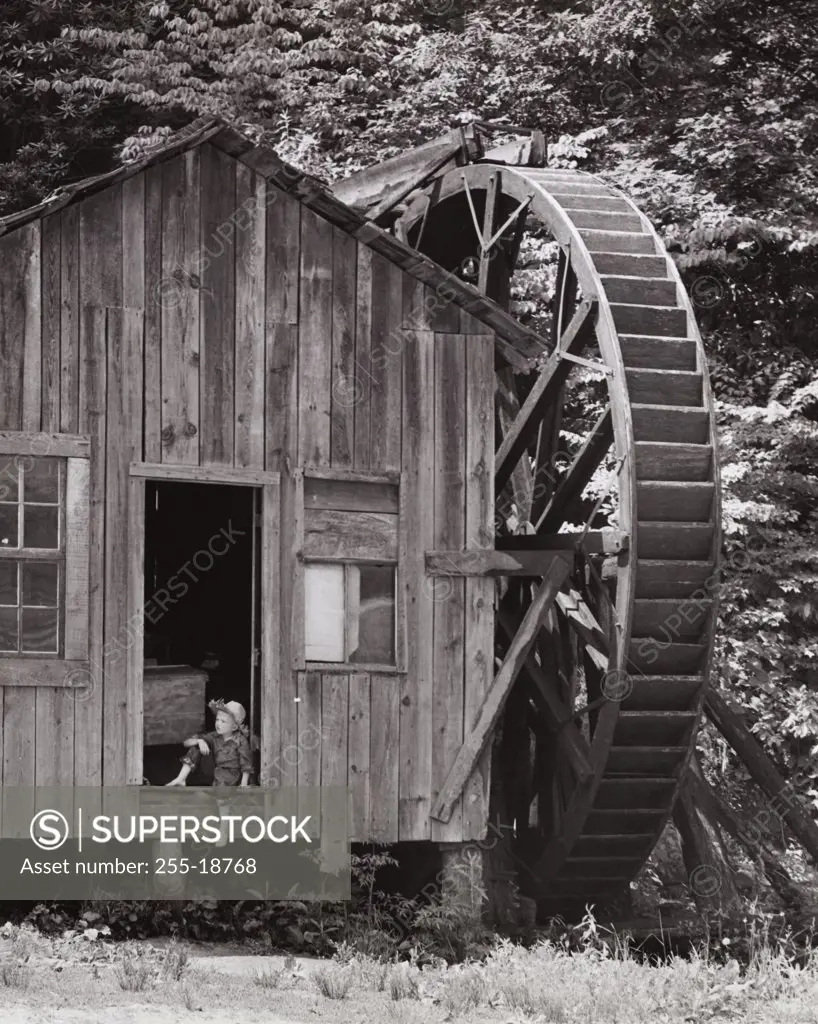 Water mill with boy sitting in door, North Carolina, USA