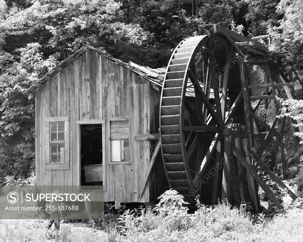 Boy standing in front of a water mill, North Carolina, USA