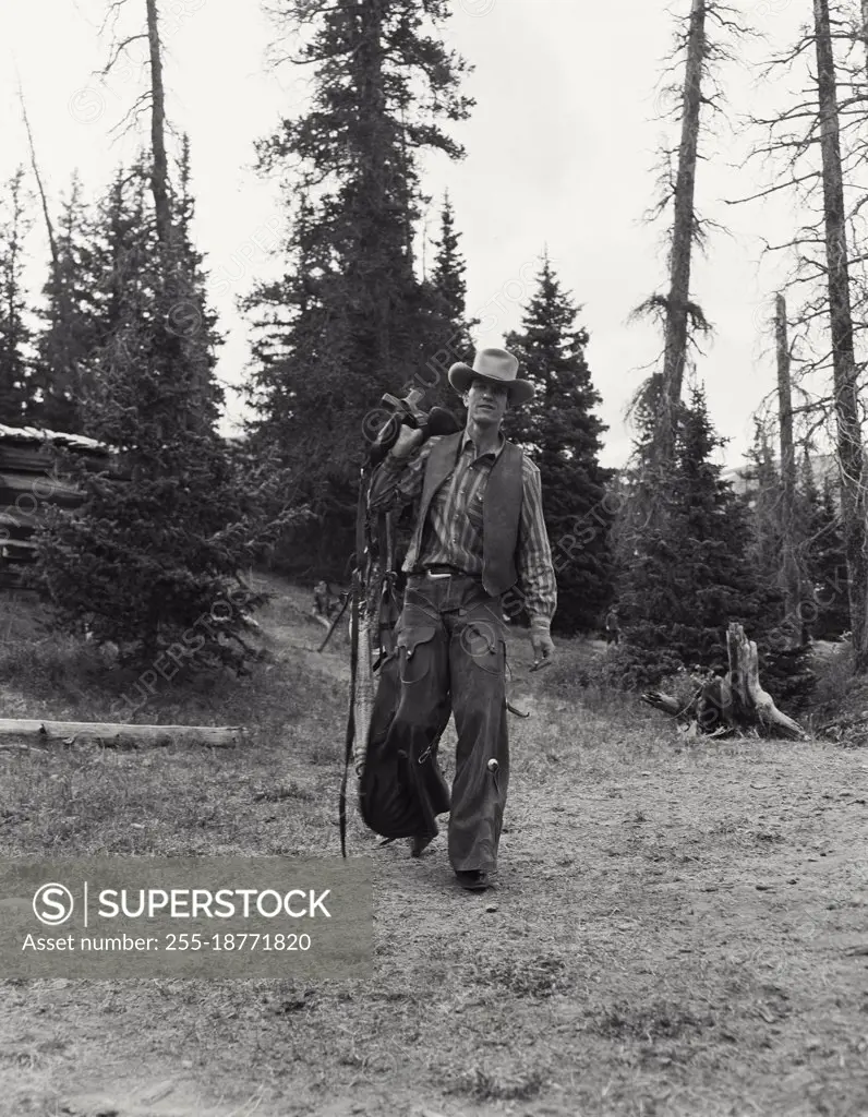 Vintage photograph. Cowboy in chaps outdoors in the woods. Model released