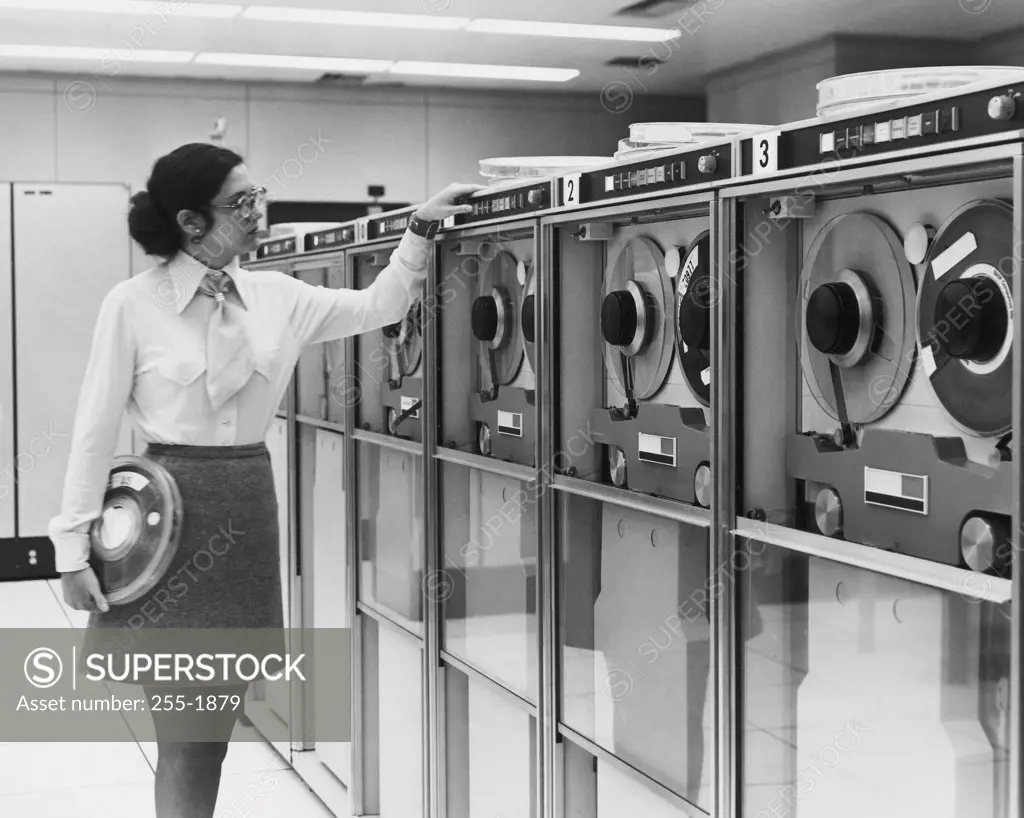 Businesswoman working with computer tape drives, 1970