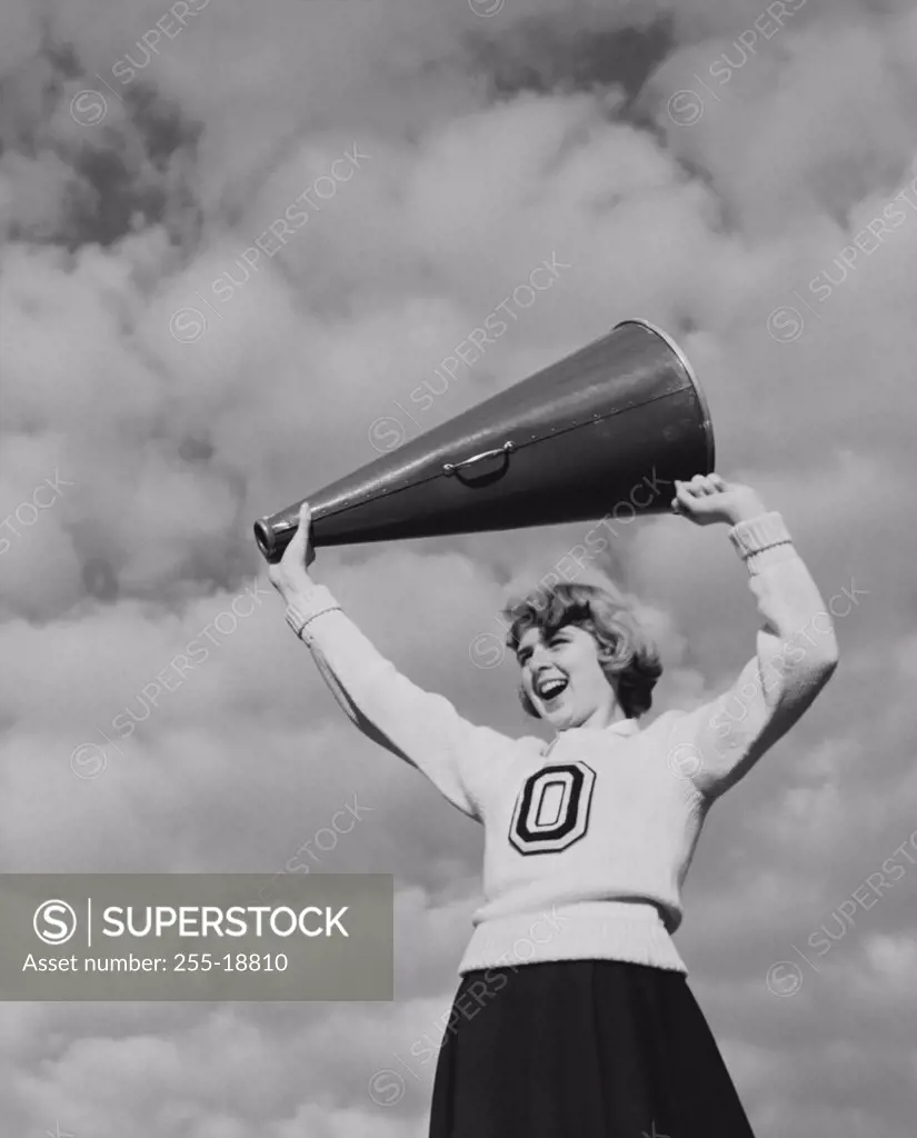 Low angle view of a female cheerleader holding a megaphone and smiling