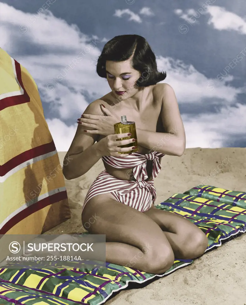Young woman applying suntan lotion on beach