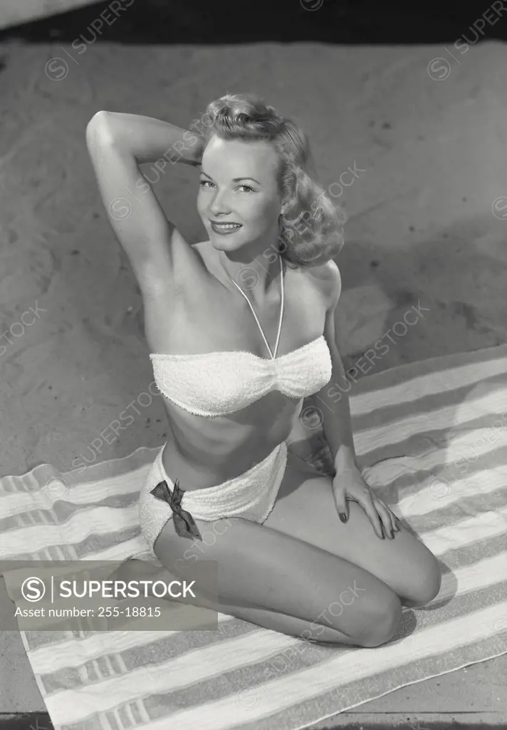 Vintage photograph. Woman in bikini sitting on beach towel.