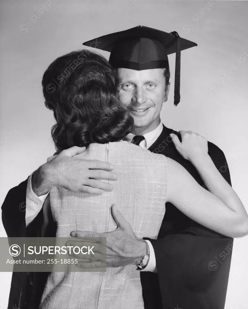 Close-up of a mid adult male graduate embracing a woman