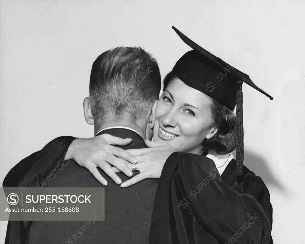 Portrait of a female graduate hugging a man