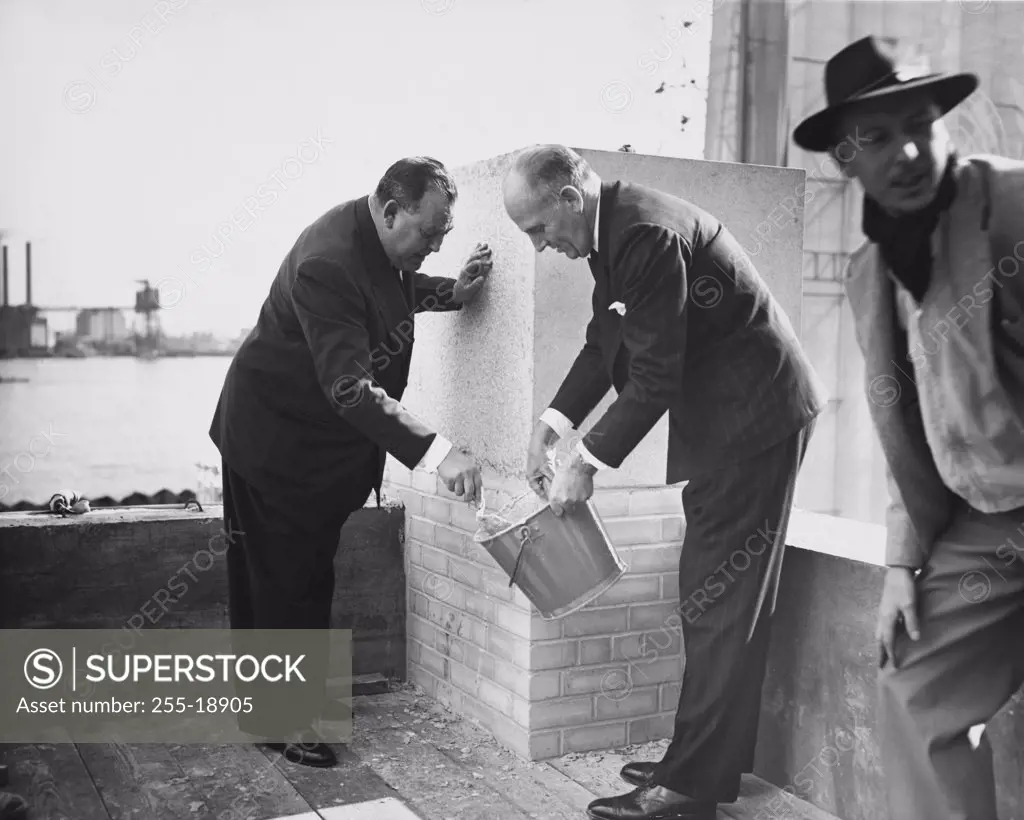 United Nations Secretary General Trygve Lie and Architect Wallace Harrison applying mortar to cornerstone of UN Headquarters building, New York City, USA October 1949