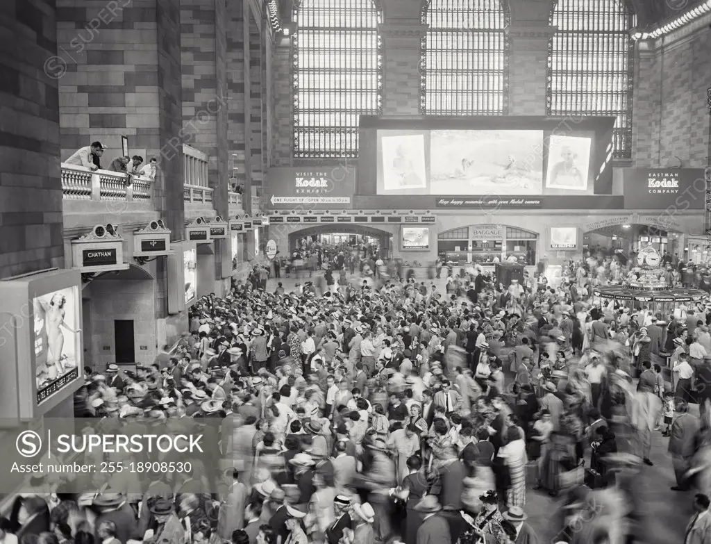 Vintage photograph. View looking at Kodak Exhibit sign behind crowd of people at a busy Grand Central Station.