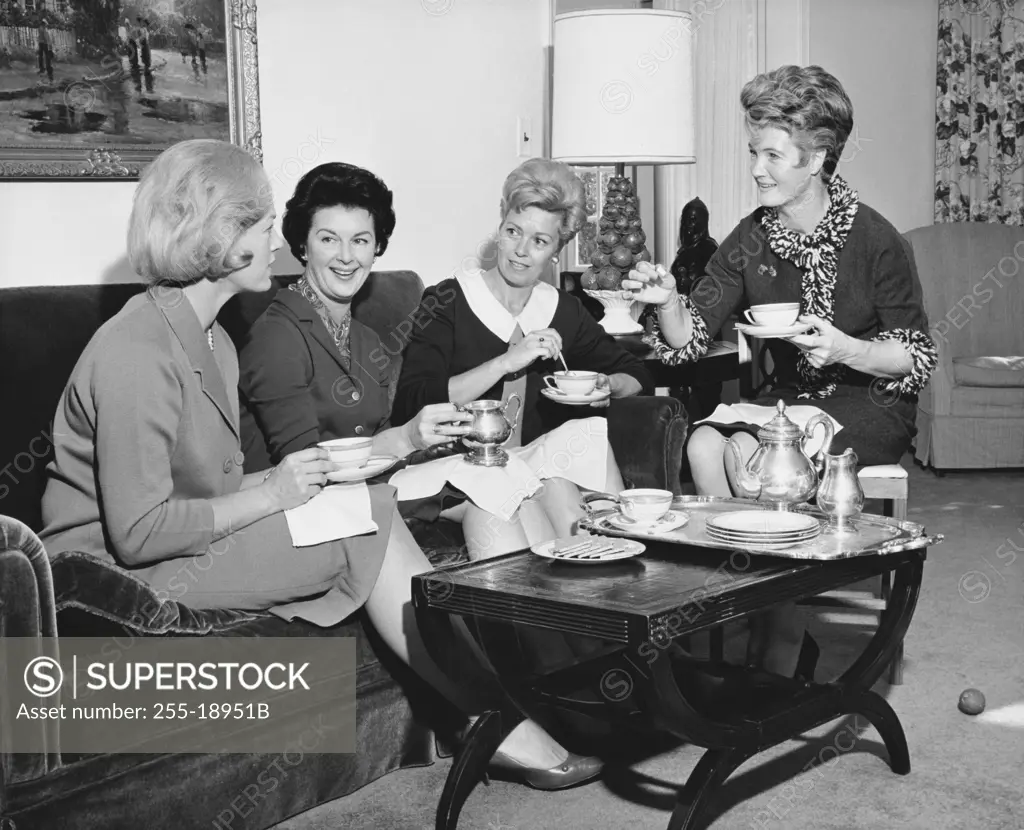 Four young women sitting together drinking tea