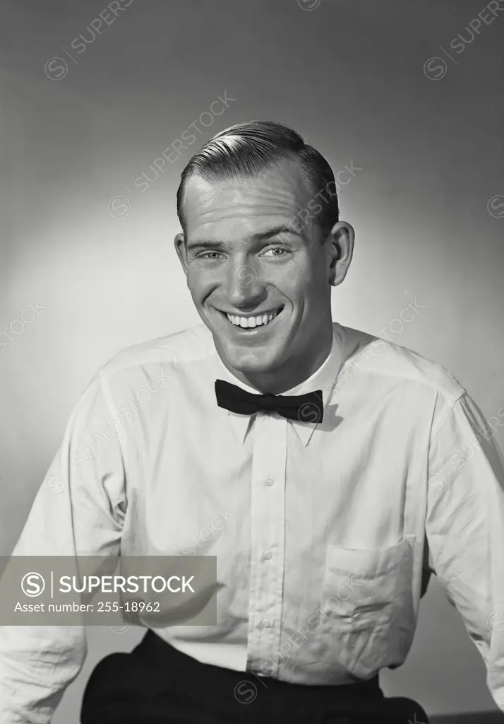 Vintage Photograph. Man dressed as bartender with white dress shirt and black bow tie smiling