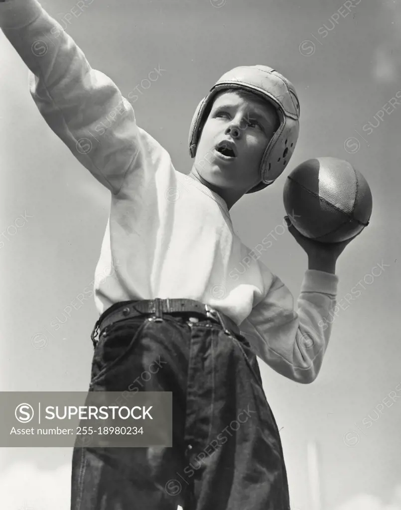 Vintage photograph. Boy wearing football helmet about to throw football