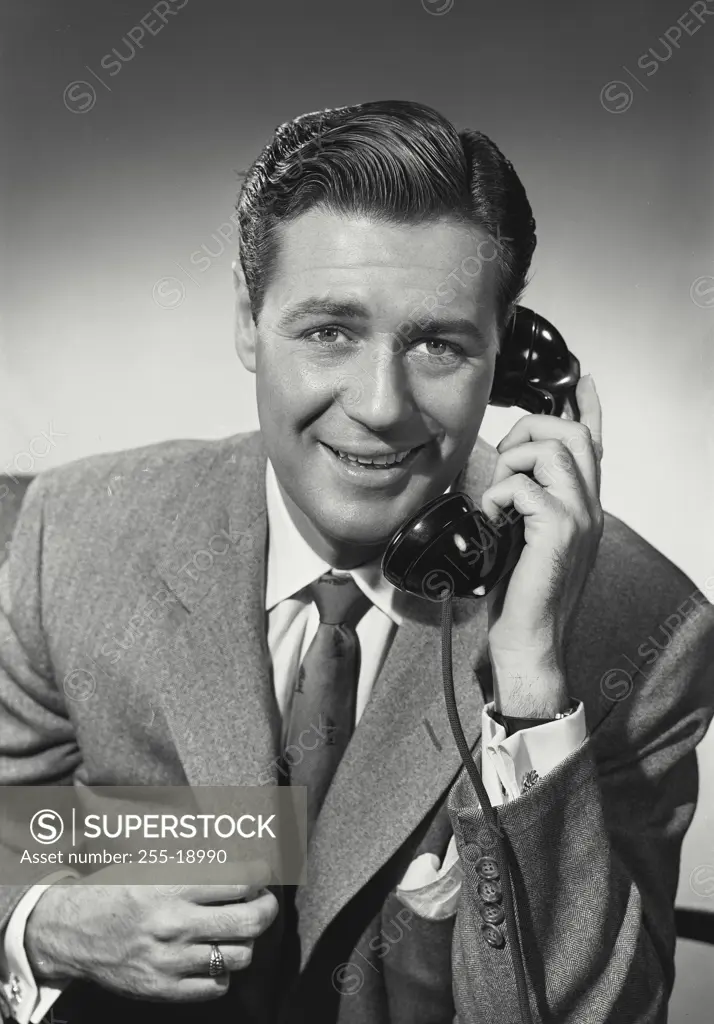 Vintage photograph. Man in suit and tie talking on telephone.