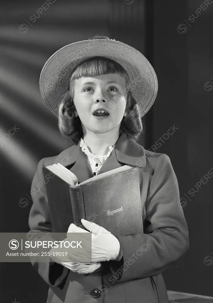 Vintage photograph. Portrait of young girl wearing straw hat with flowers holding hymnal book