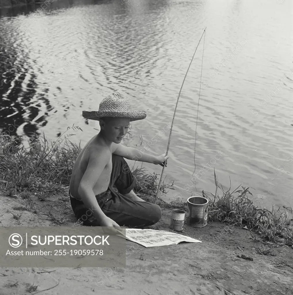 Vintage photograph. Boy reading comics while fishing