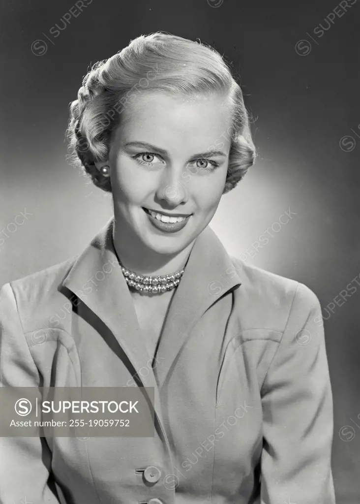Vintage photograph. woman with short hair in coat smiling at camera.