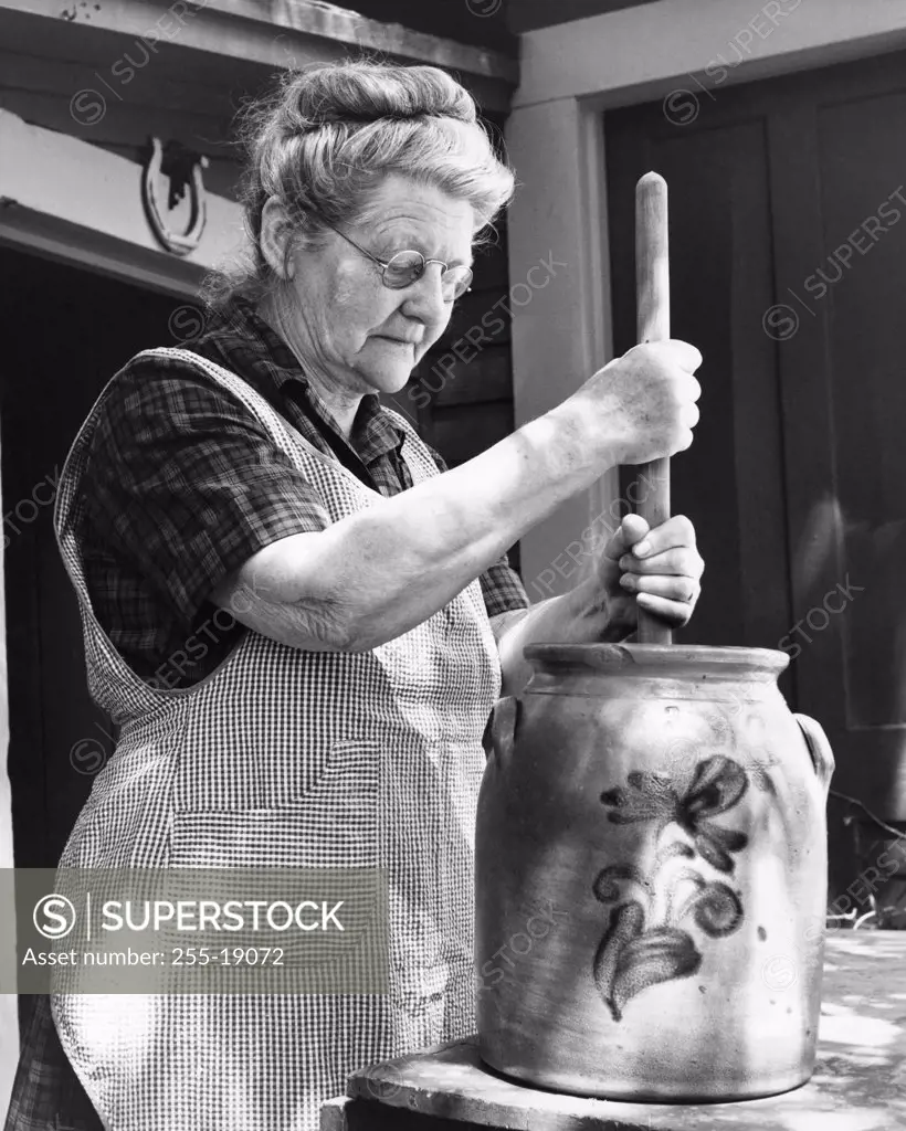 Side profile of a senior woman churning butter