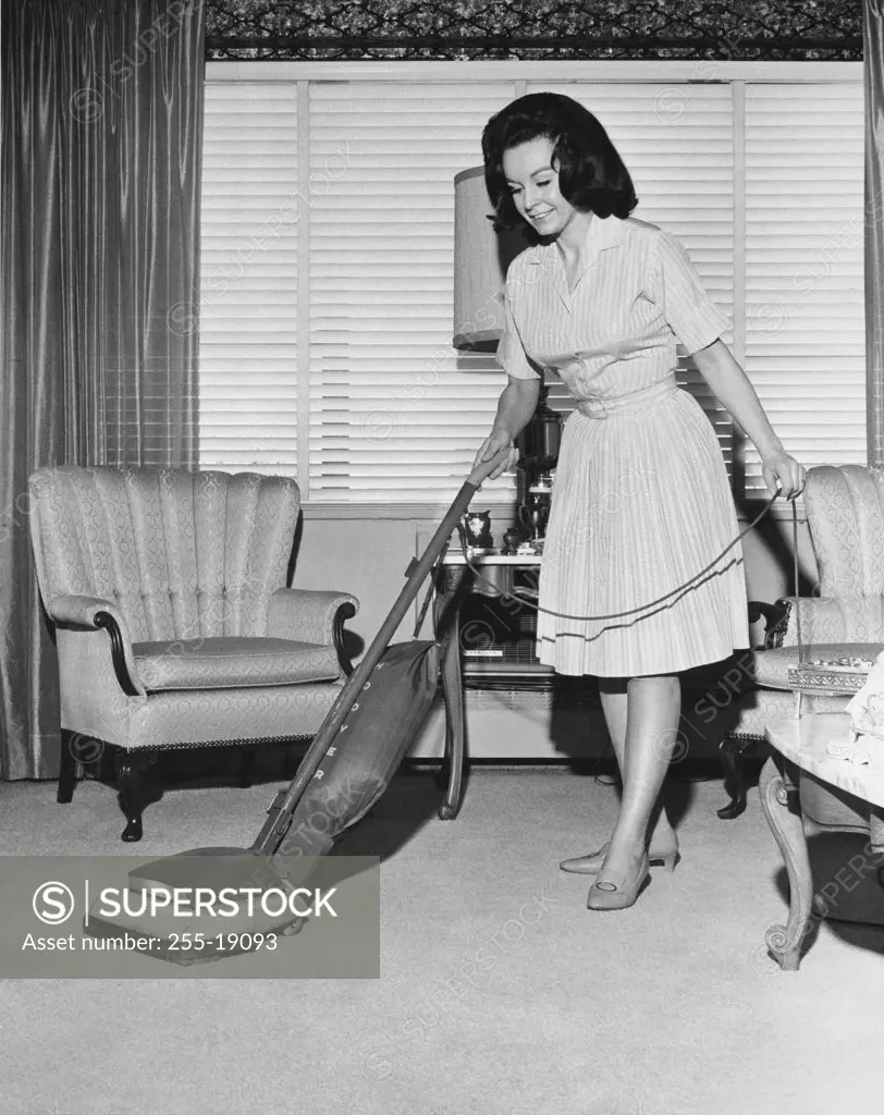 Young woman cleaning carpet with a vacuum cleaner