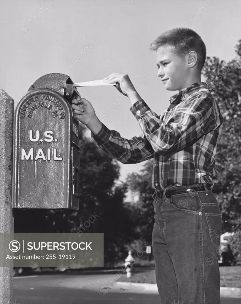 Side profile of a boy dropping mail in a mailbox