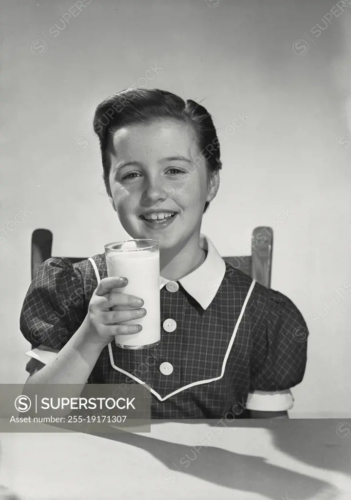 Vintage photograph. young girl in dress holding glass of milk