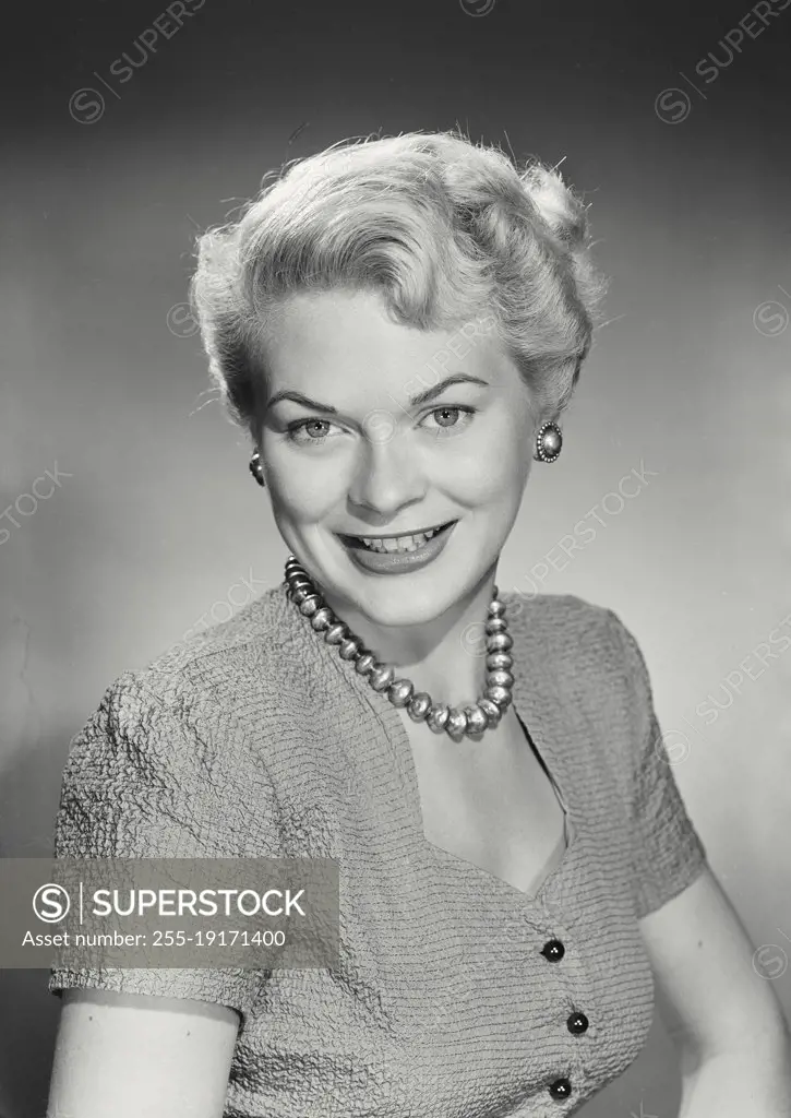 Vintage photograph. Portrait of smiling woman with blonde hair wearing necklace and button up blouse