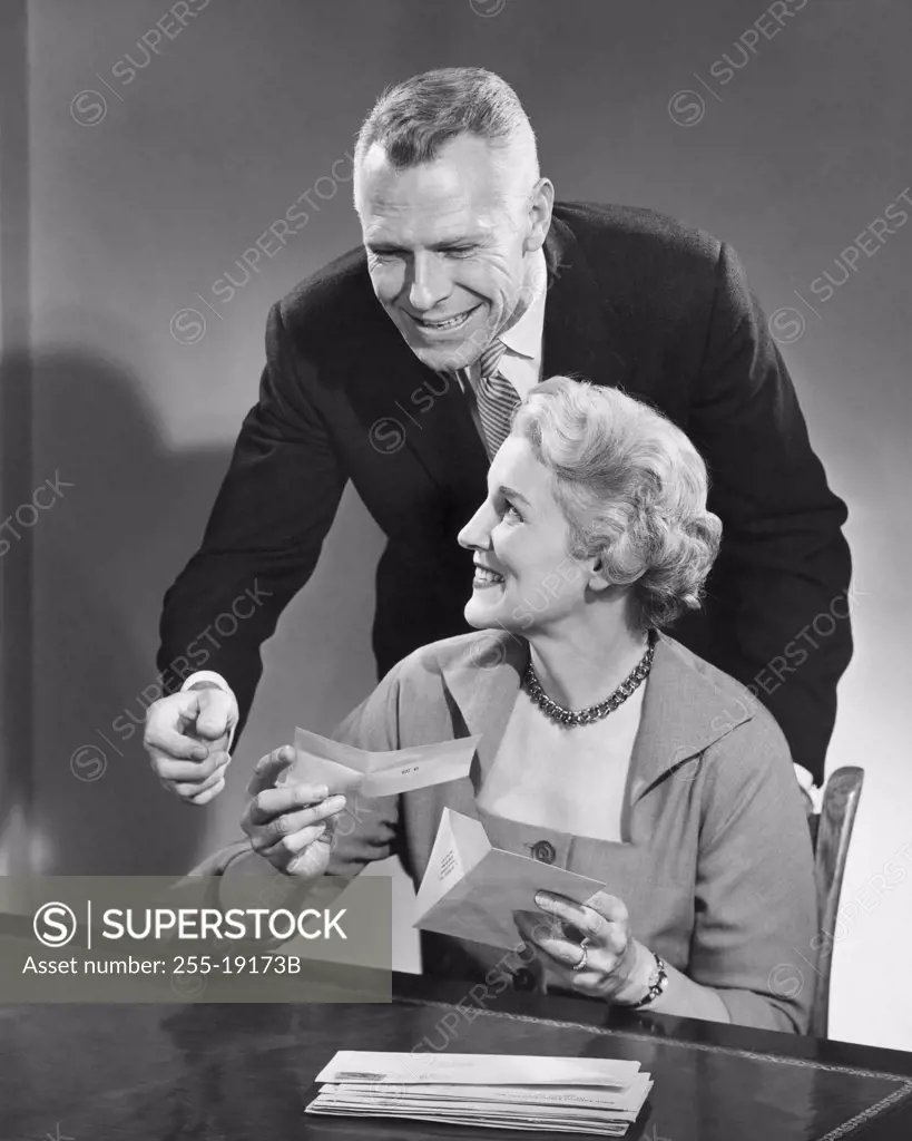 Senior woman holding a check with a mature man standing behind her