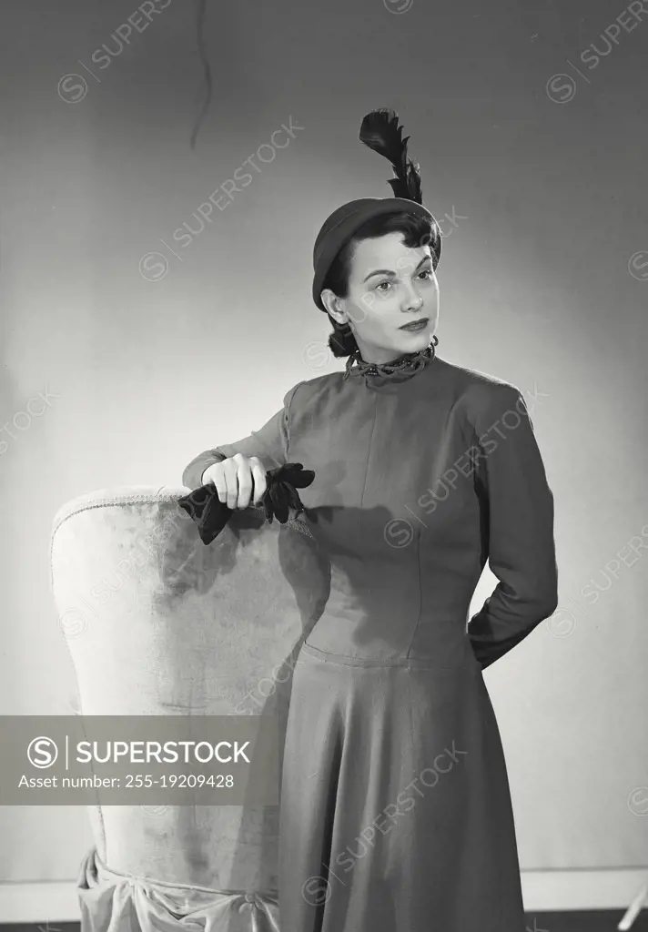 Vintage photograph. Fashionable woman leaning on high backed chair