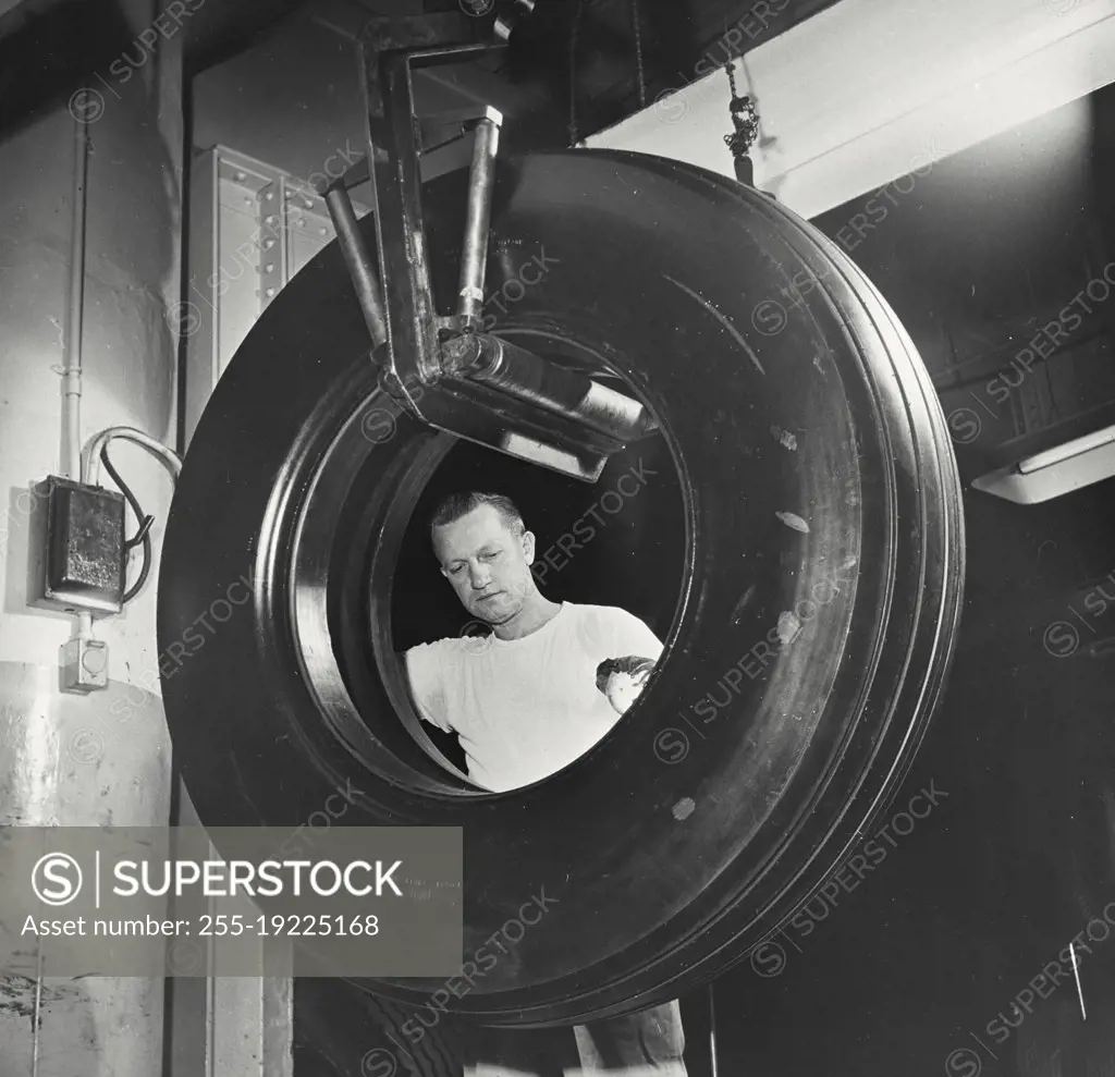 Vintage photograph. Inspecting an airplane bomber tire at a US Rubber Company plant