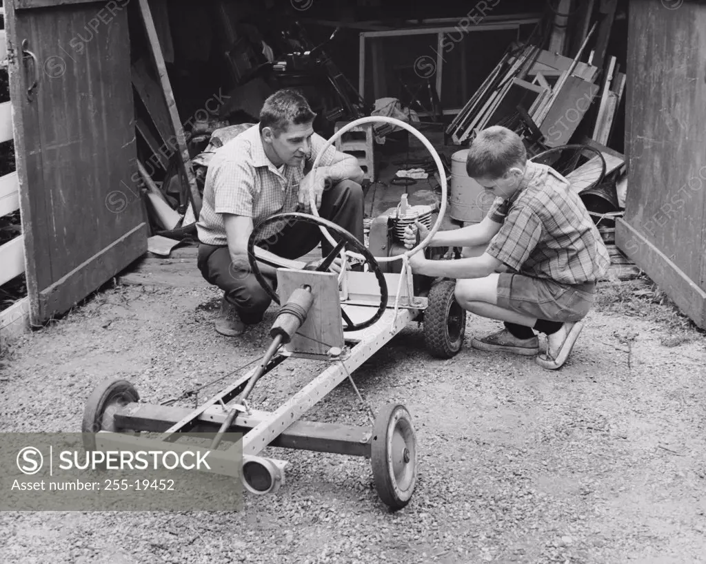 Side profile of a boy with his father making a model of a car