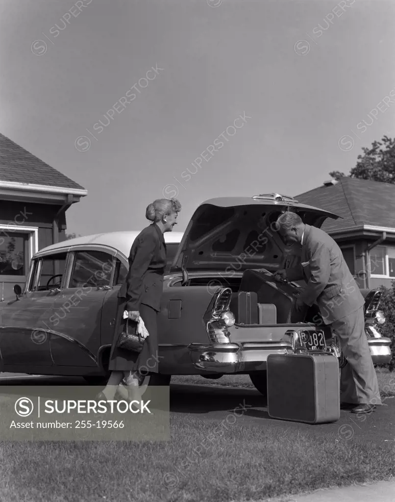 Senior couple loading suitcase into a car