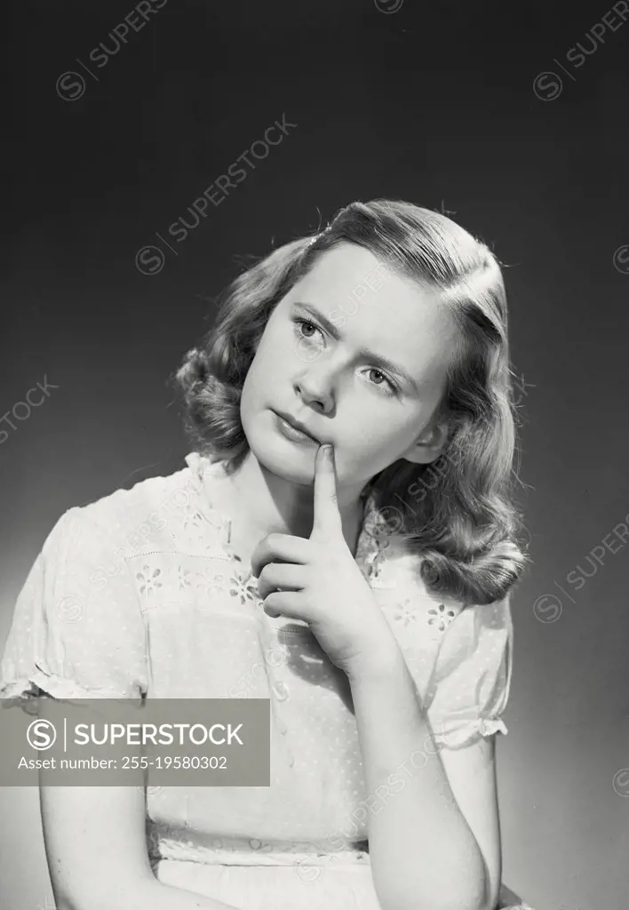 Vintage photograph. Young girl in dress with finger on chin