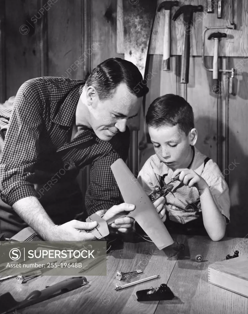 Close-up of a mature man with his son making a model of an airplane