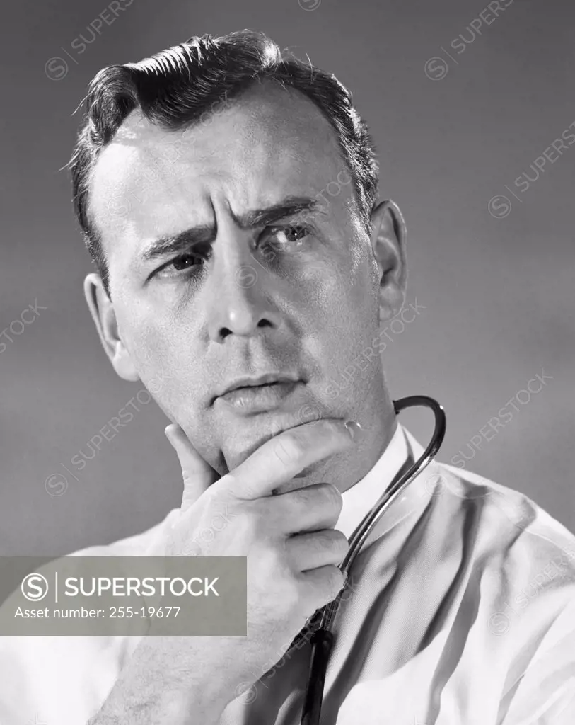 Vintage Photograph. Portrait of man in doctors uniform with concerned expression and hand on chin