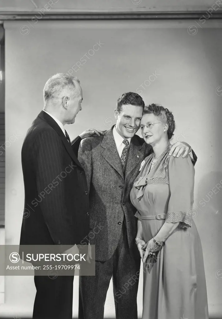 Vintage photograph. Young man standing with mother and father smiling