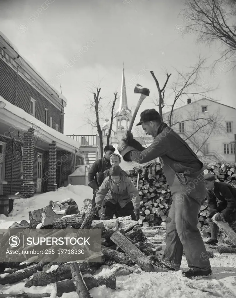 Vintage photograph. Men chopping firewood in snow with church in distance