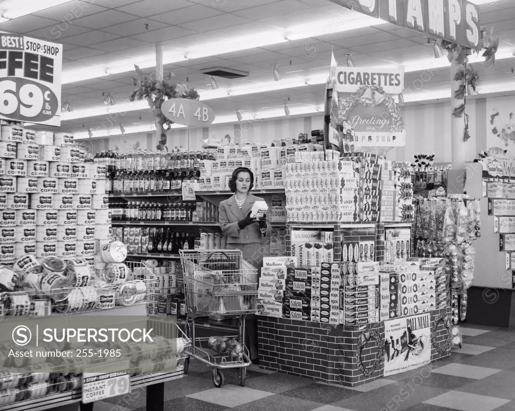 Young woman standing next to a cigarette display in a grocery store