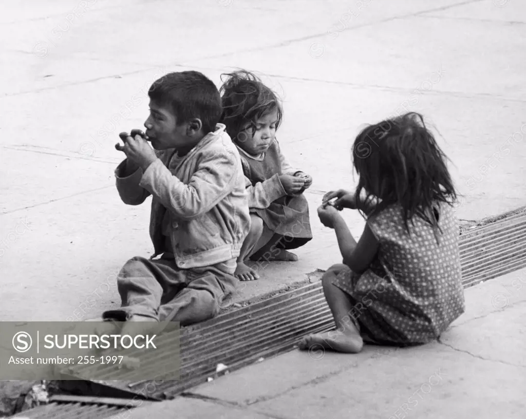 Boy and two girls sitting on a road, Mexico