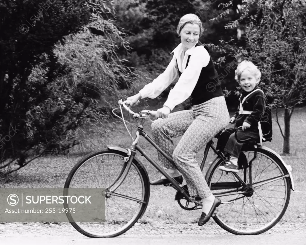 Side profile of mother cycling with daughter sitting behind her
