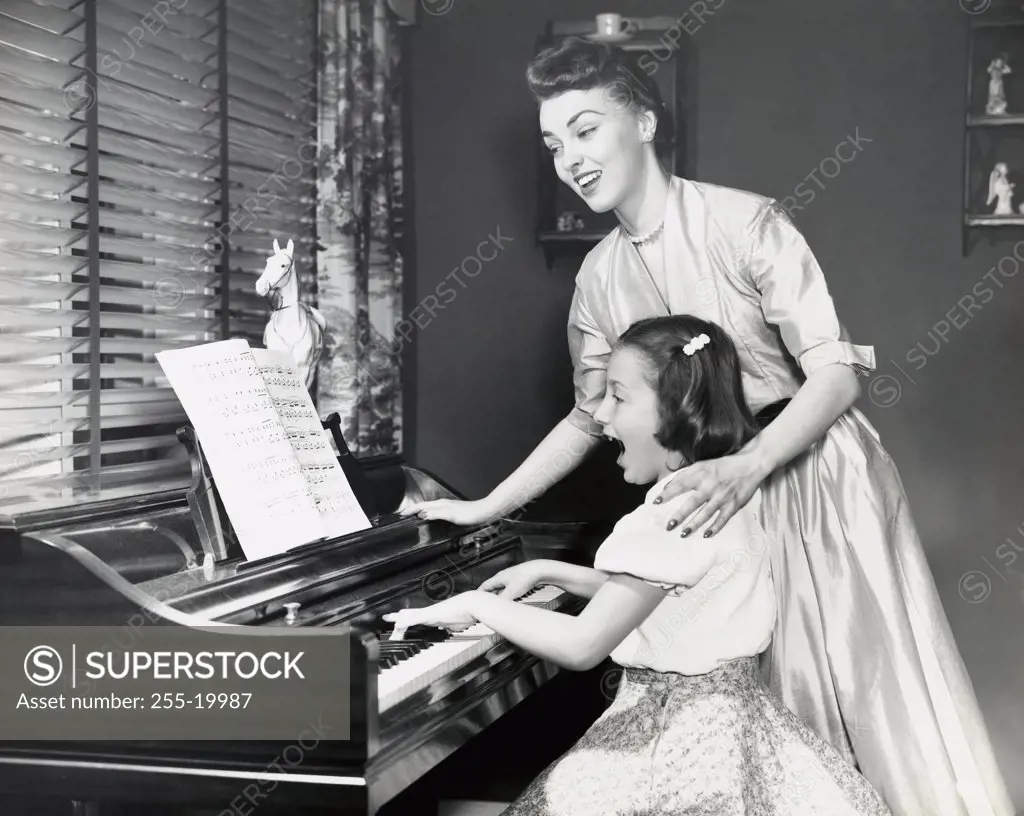 Close-up of mother teaching daughter to play piano