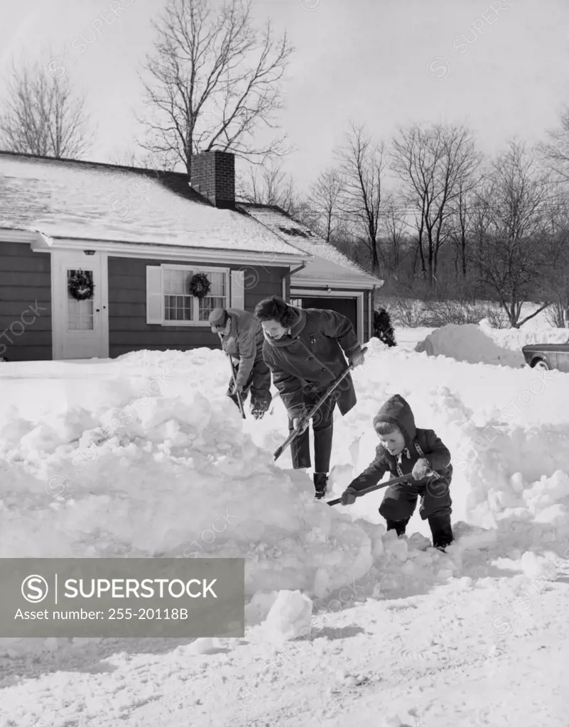 Side profile of parents and their son shoveling snow
