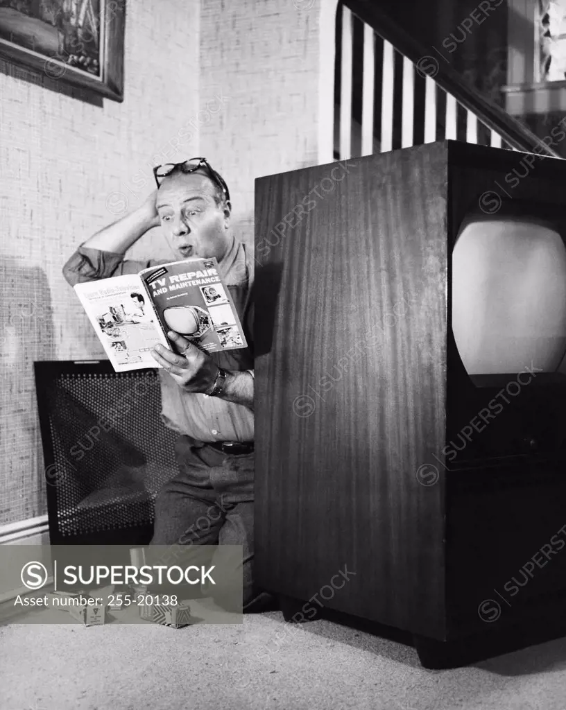 Man struggling to repair a television