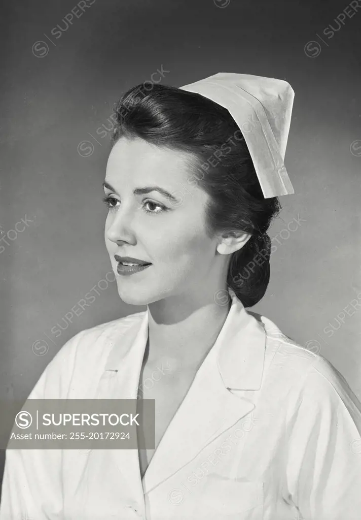 Vintage photograph. quarter profile view of brunette woman wearing nurse's uniform